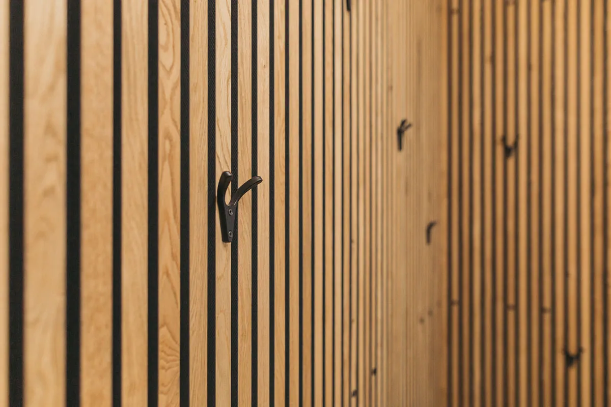 Garderobe mit Holzlamellen-Wand und schwarzen Haken